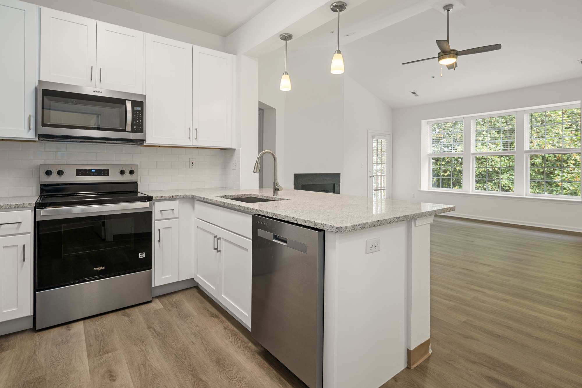 Kitchen at Jacobs Woods showcasing the island, stainless steel dishwasher, and open layout into the living area.