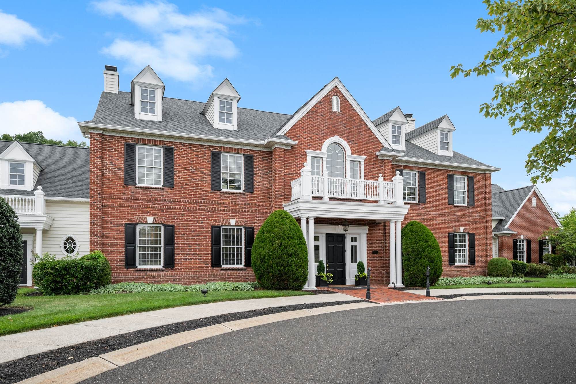 Jacobs Woods exterior featuring a red-brick, colonial-style building with white trim and manicured landscaping.