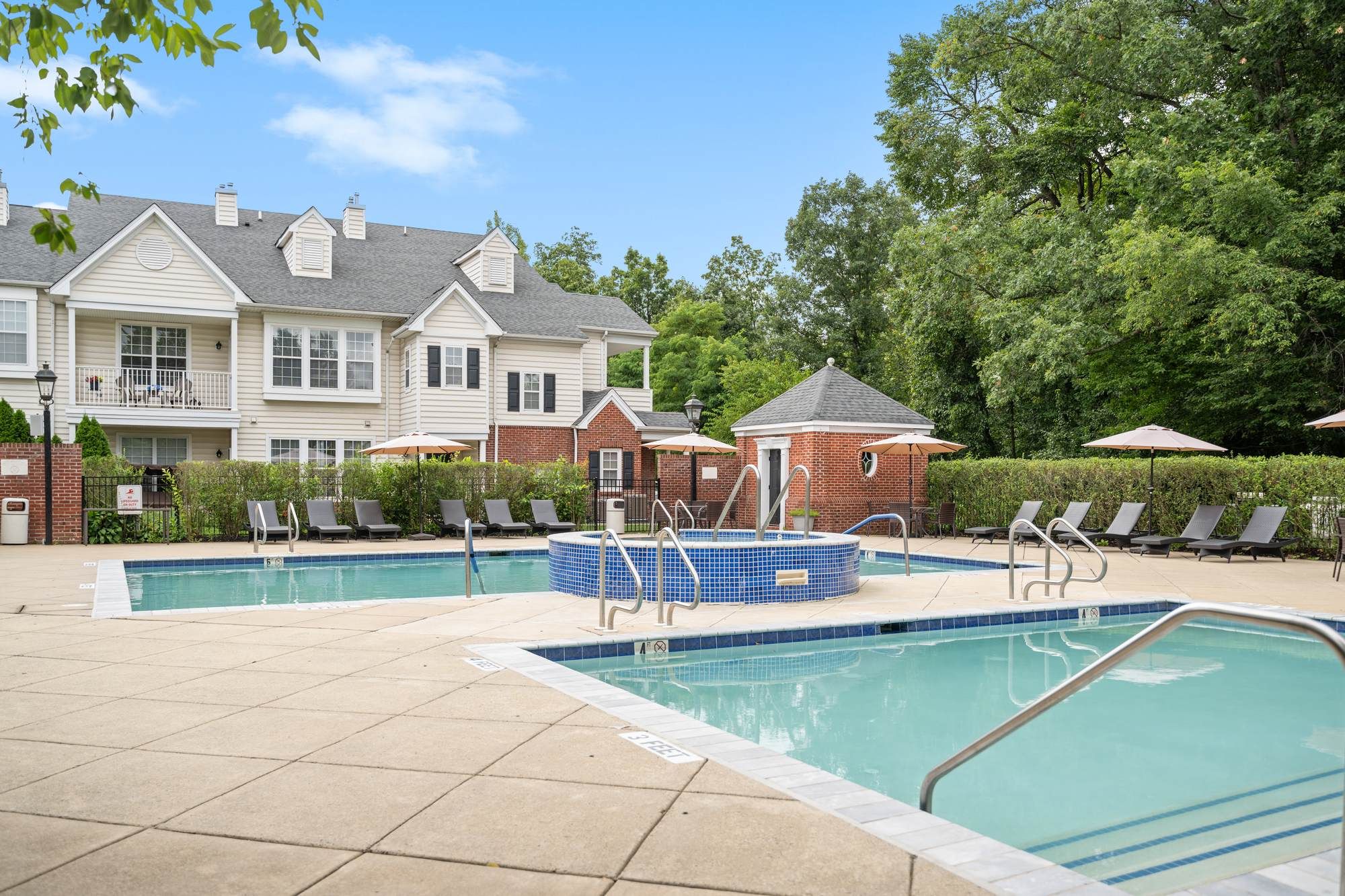 Outdoor swimming pool and spa area at Jacobs Woods with lounge seating and surrounding greenery.