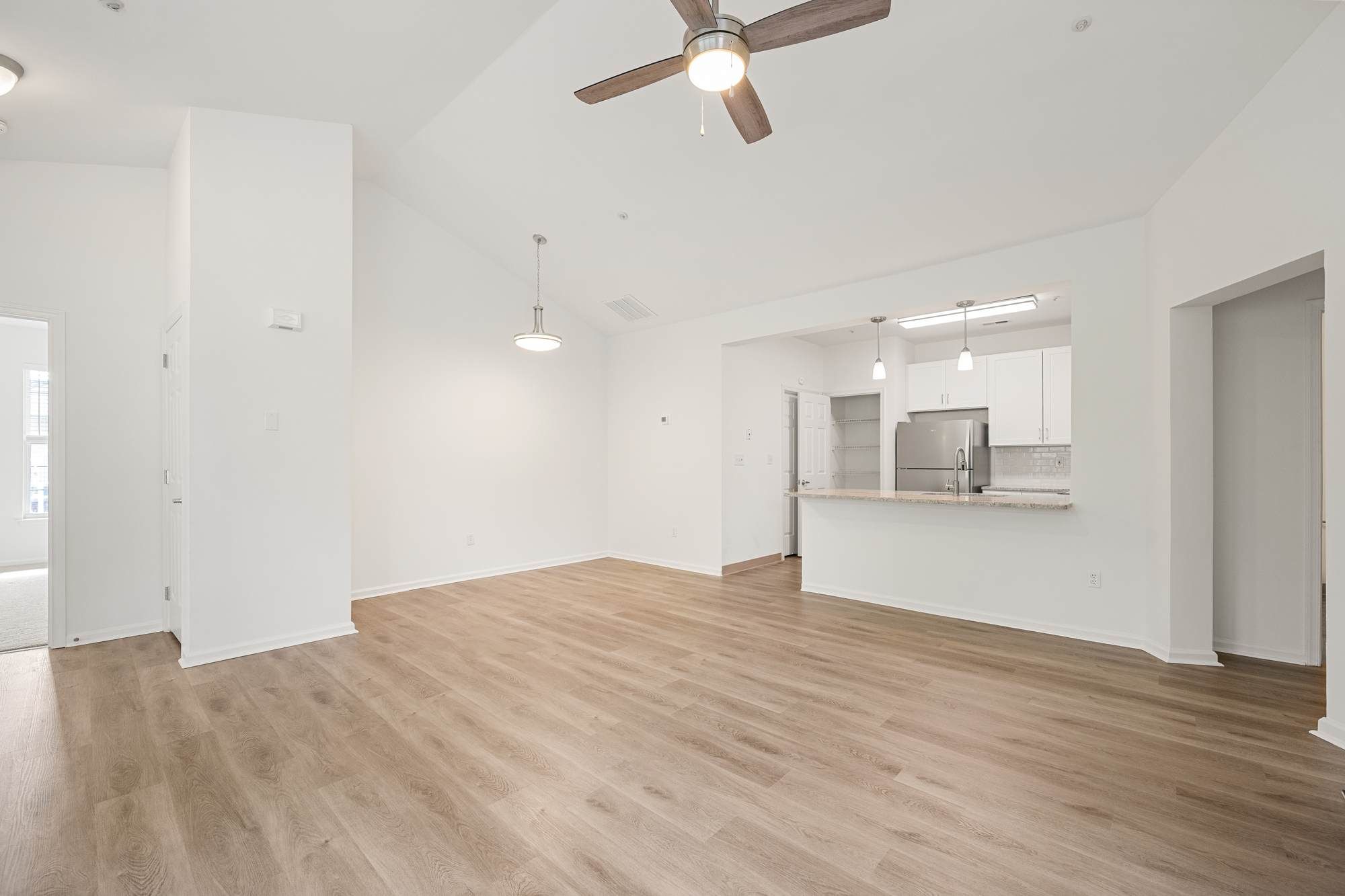 Open-concept living and dining area with wood-style flooring and ceiling fan.