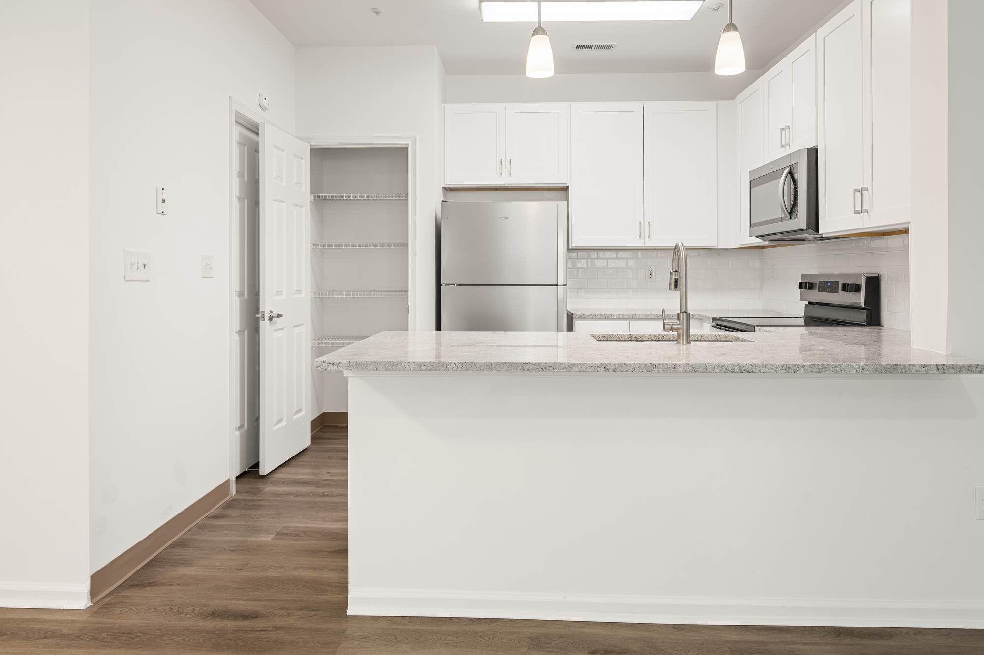 Modern Jacobs Woods kitchen with white cabinetry, stainless steel appliances, and a large center island.