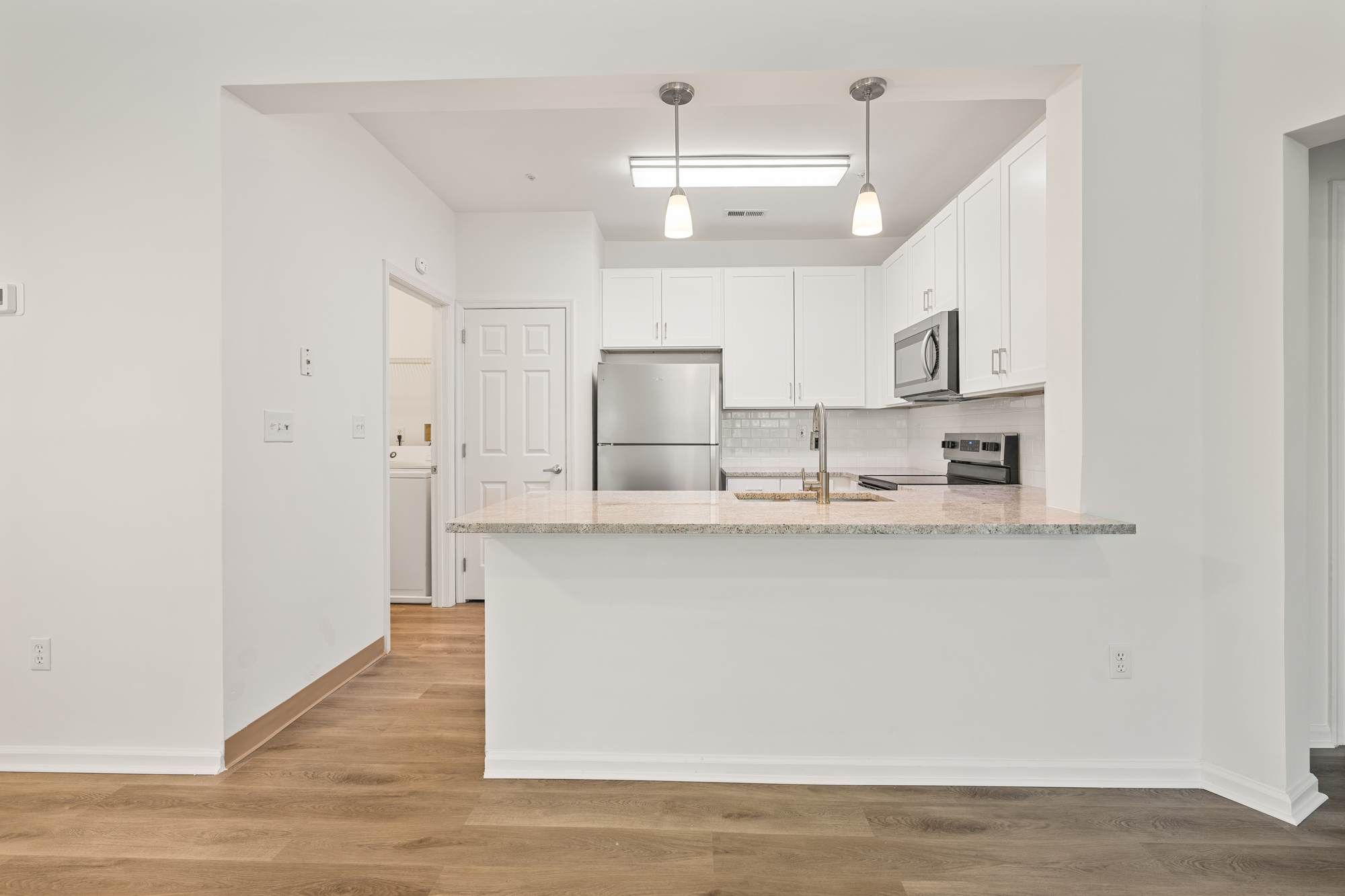 Bright Jacobs Woods kitchen with stainless steel appliances, pendant lighting, and spacious island countertop.